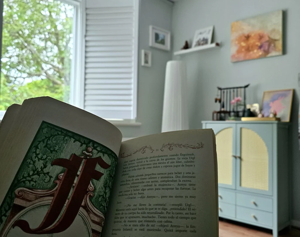 Open illustrated book with framed painting in a softly lit room